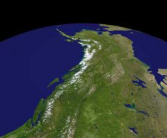 Satellite image of the Earth's surface showing a region with mountains, green terrain, and surrounding bodies of water.