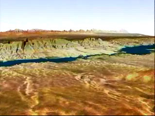Aerial view of a desert landscape with a winding river or lake running through rocky terrain, under a clear blue sky.